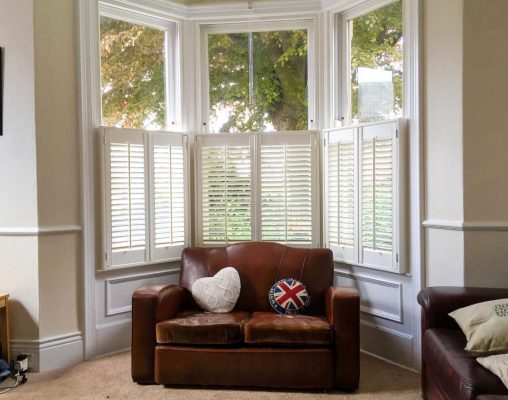 White plantation shutters fitted to a curved bay window in a living room