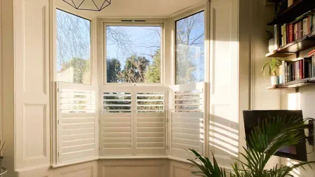 Custom café style shutters fitted around a sunny bay window
