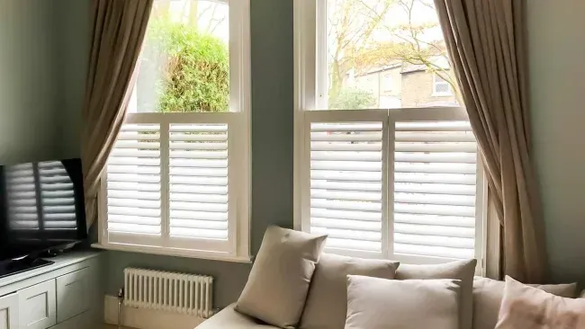 White café style shutters providing privacy in a cozy living room