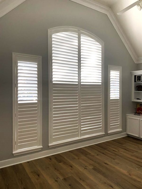 Tall white plantation shutters providing privacy in a bright room