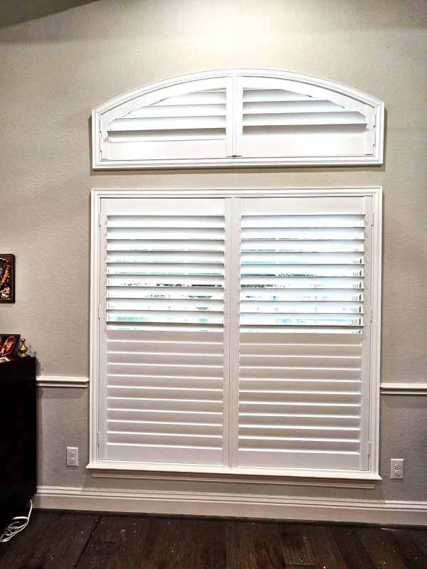 White plantation shutters providing light control on a wide window