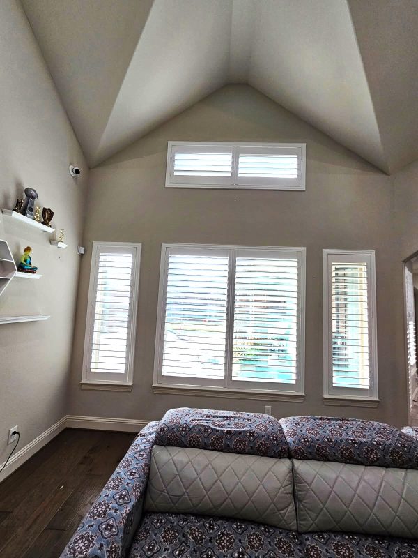 Custom plantation shutters installed below bedroom transom windows
