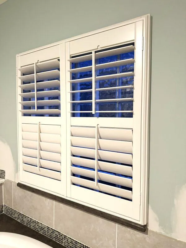 White plantation shutters with independently adjustable upper and lower louvers