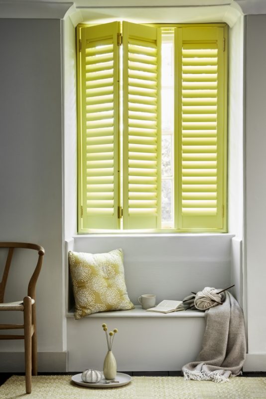 Green tier-on-tier shutters creating privacy above a window seat