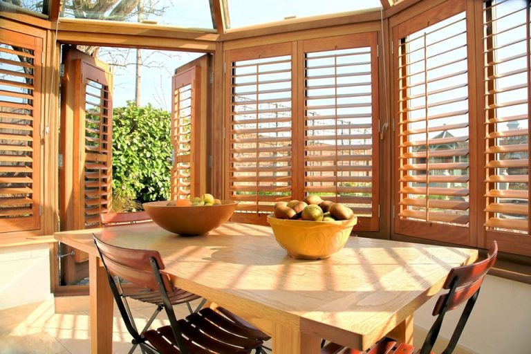 Natural wood tier-on-tier shutters surrounding a bright dining area