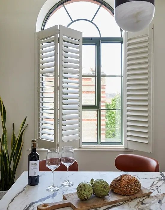White tier-on-tier shutters fitted to a tall feature window
