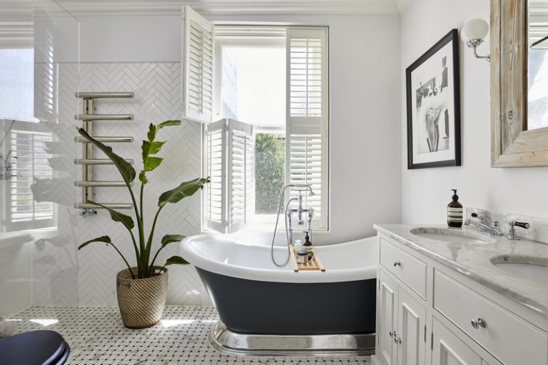 White tier-on-tier shutters installed above a freestanding bathtub