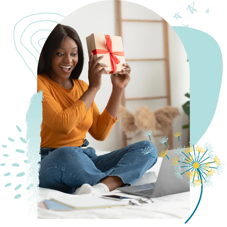 Lady in front of laptop smiling and holding up gift