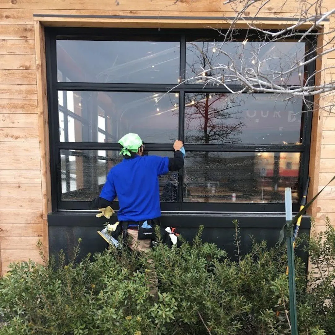 Commercial window cleaning service San Antonio - technician cleaning modern office building exterior windows with professional equipment
