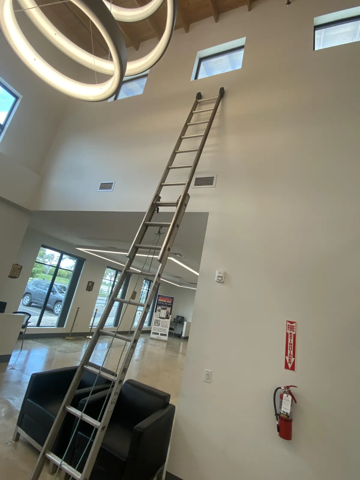 San Antonio commercial window cleaning service with professional ladder setup for tall interior windows in modern office space