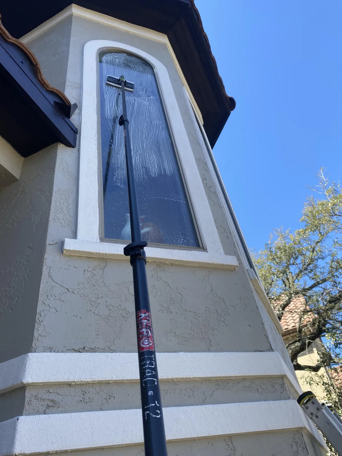 Professional window cleaning in San Antonio using water-fed pole system on residential home exterior windows