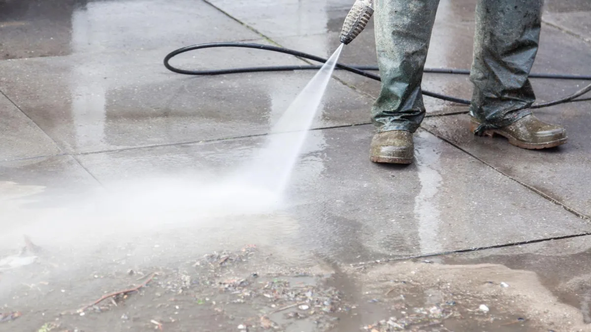 DND Window Cleaning technician performing pressure washing on driveway in San Antonio