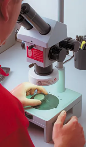 Technician using a microscope for high-magnification inspection to ensure proper bonding and accurate dimensions at High Tech Elastomers.