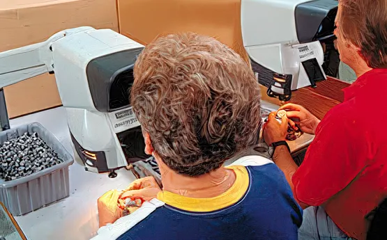 Technicians inspecting, cleaning, and deflashing bonded components at 5X magnification to ensure quality and performance at High Tech Elastomers.