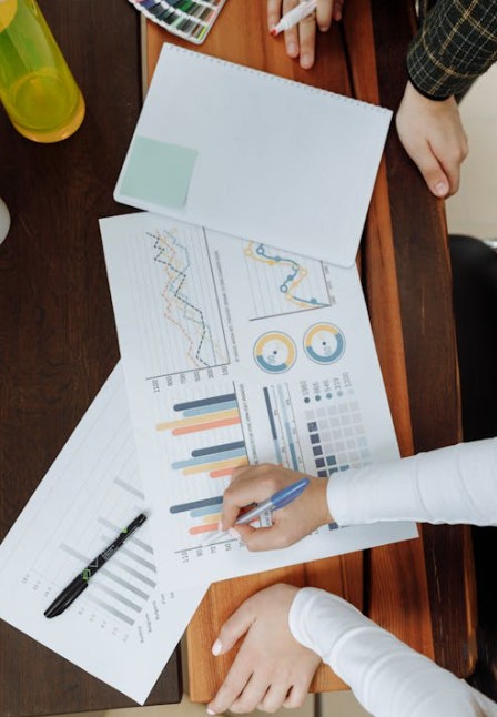 lady writing on a page with reports graphs and tables