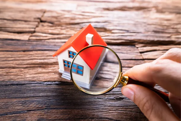 Buyer’s home inspection with magnifying glass examining a house model
