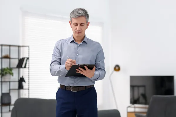 Professional home inspector reviewing inspection notes inside a residential property
