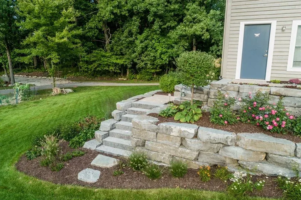 Stone steps leading up to a house, surrounded by landscaped garden beds with various plants and flowers, showcasing a well-maintained outdoor space in Sydney.