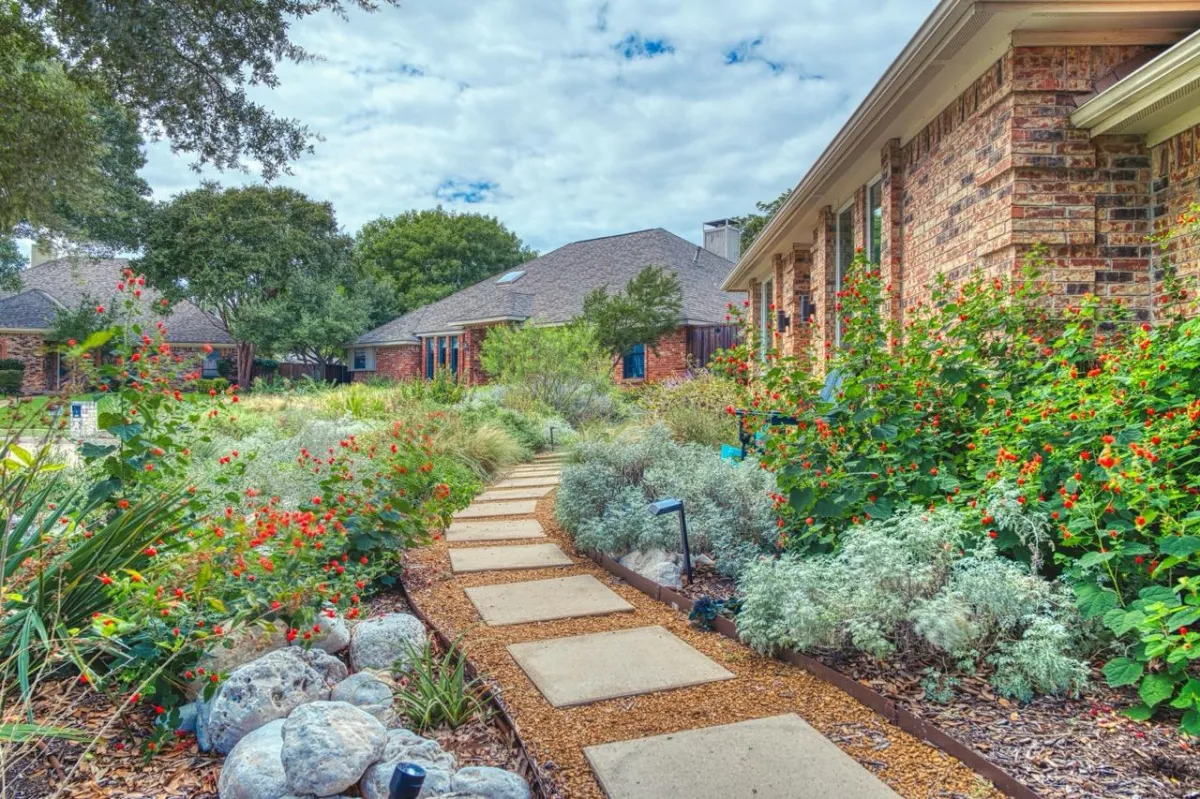 Lush garden pathway with vibrant flowers, stone edging, and landscaped greenery, showcasing tailored outdoor design by Aussie Pergolas & Landscapes in Sydney.