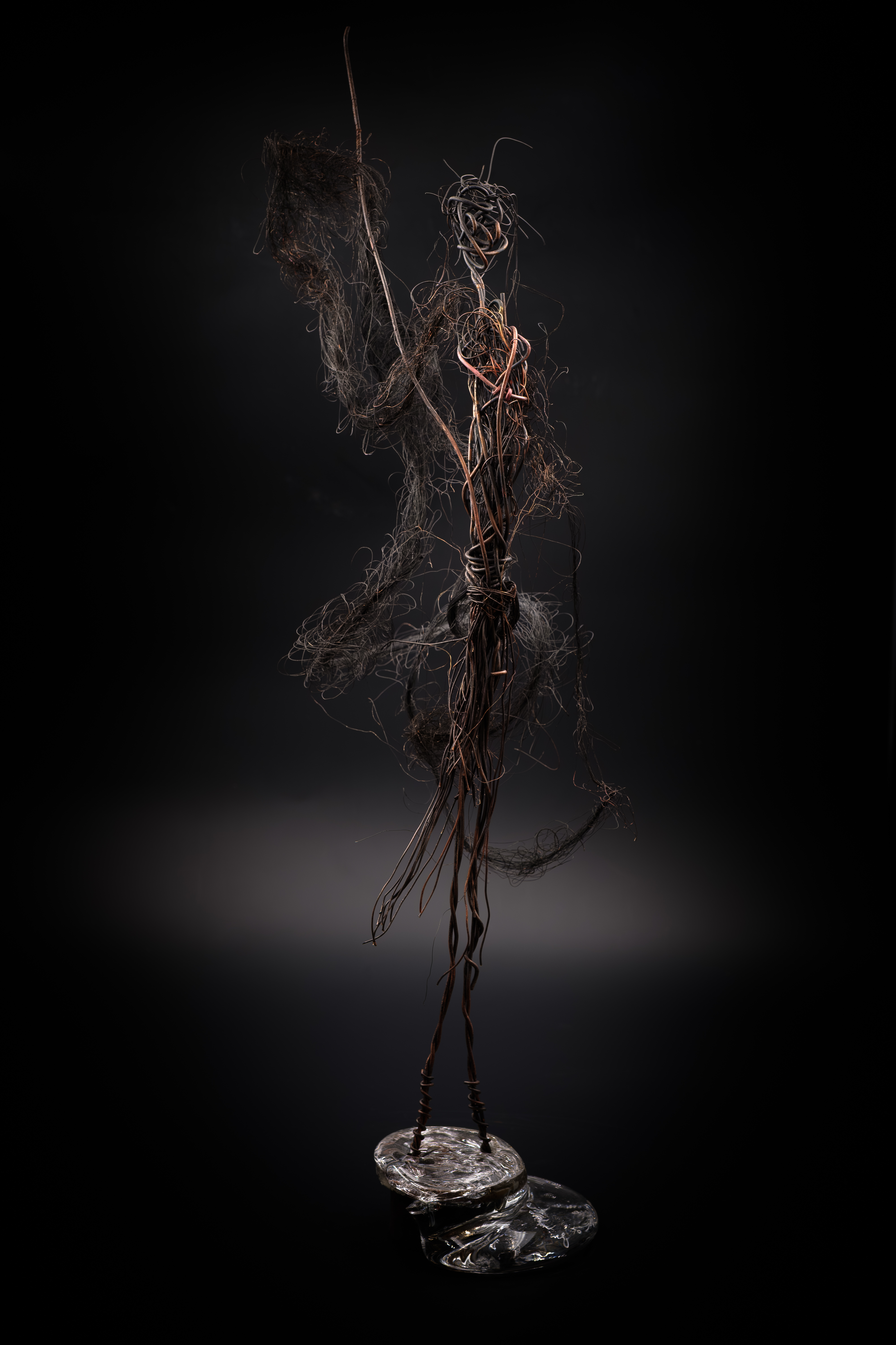 Escultura figurativa de madera oscura, detalles tallados a mano, fondo beige suave, luz natural, estilo minimalista, composición centrada, transmite calidez y tradición.