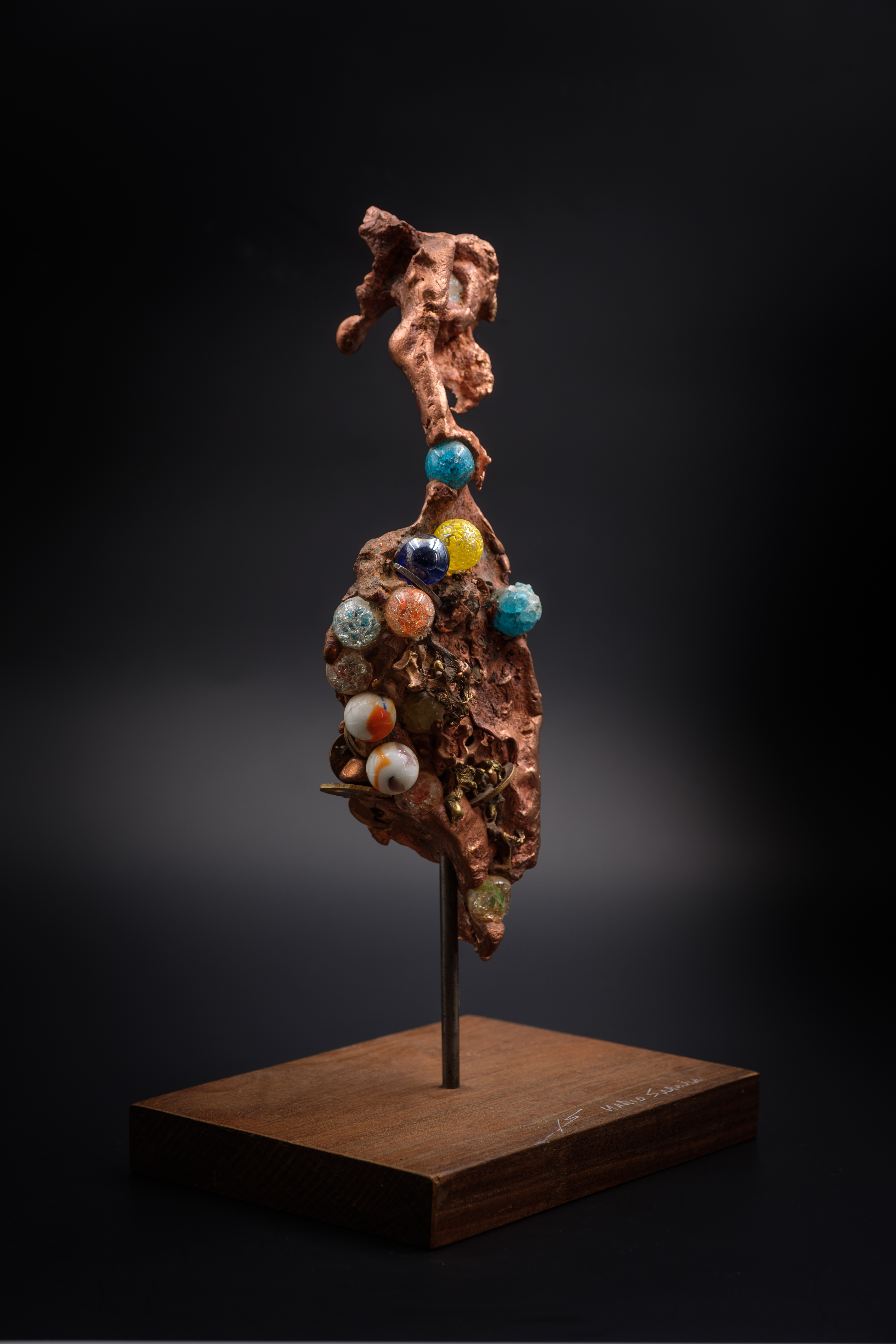 Escultura contemporánea de bronce pulido, forma orgánica, sobre base de mármol negro, fondo neutro, luz dirigida, estilo minimalista, composición vertical, transmite sofisticación y movimiento.