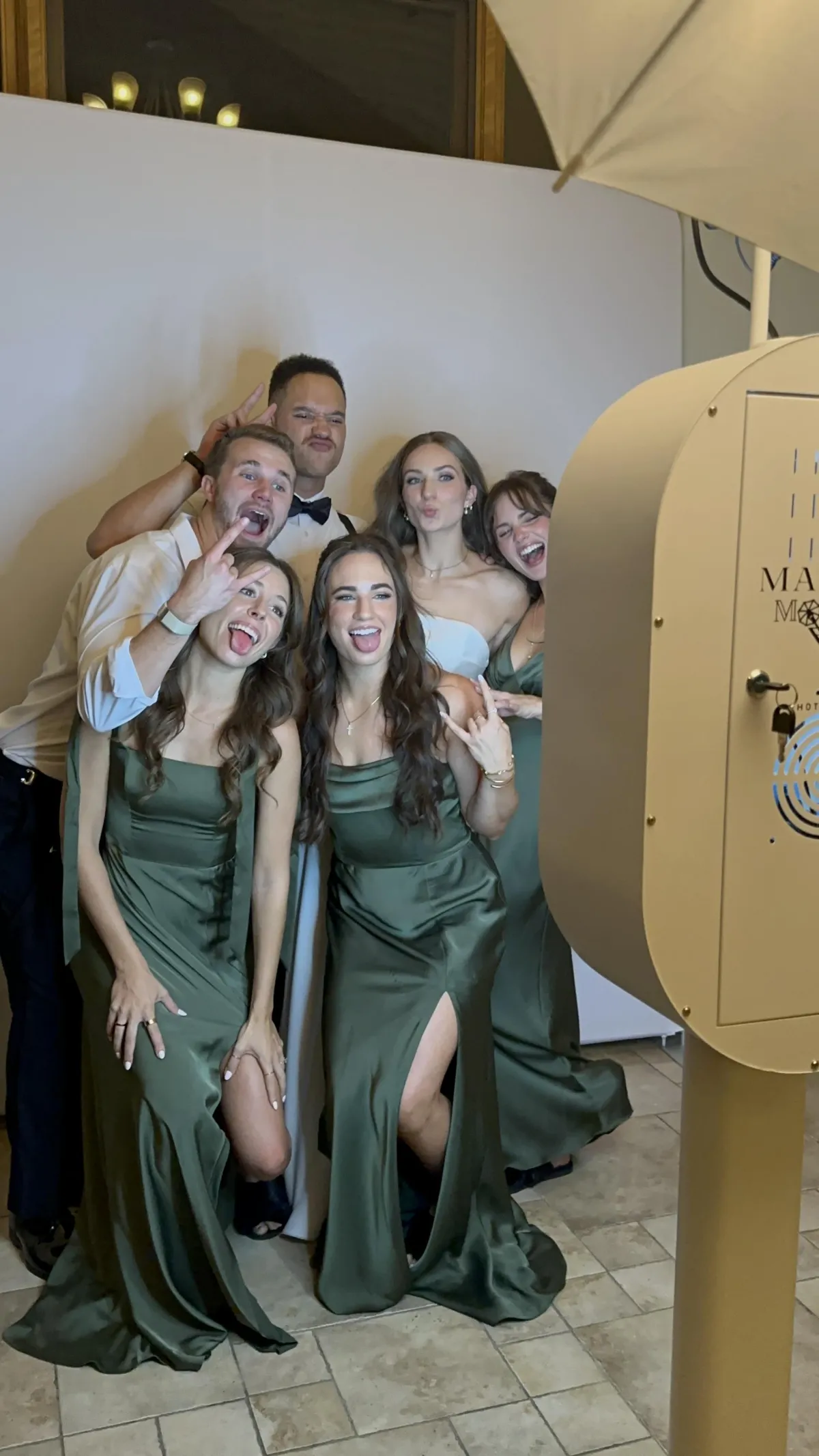 Team members laughing during a luxury open-air photo booth session at a company holiday party