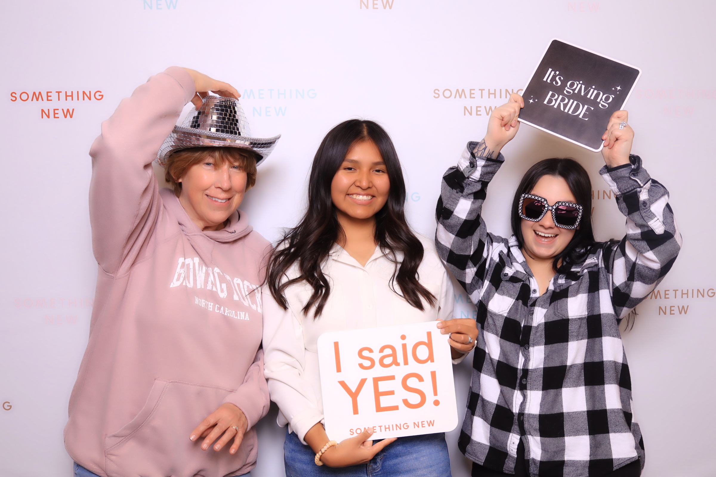 Bride and bridesmaids posing in a wedding photo booth rental in colorado springs at something new boutique