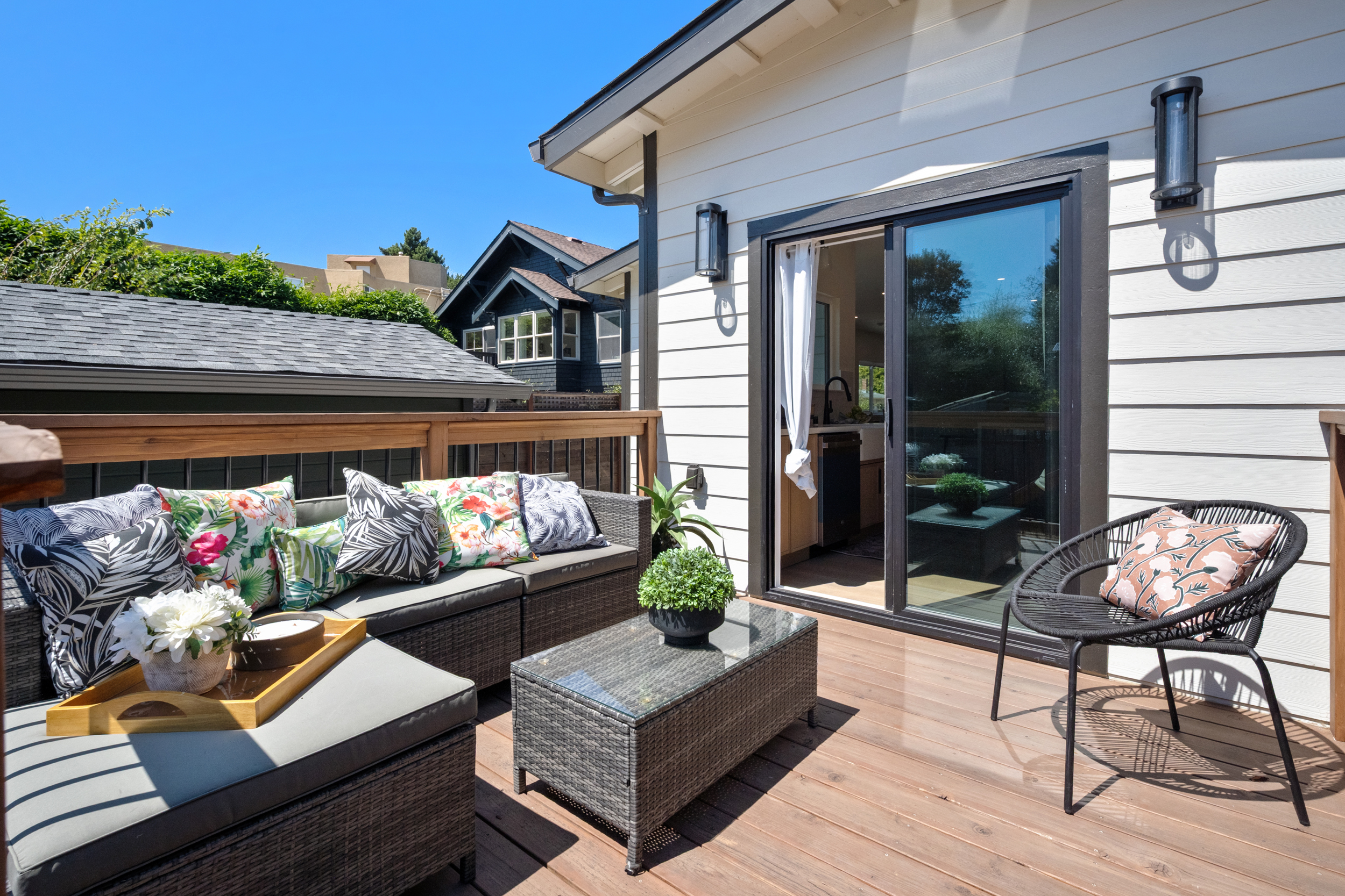 Outdoor deck with lounge seating, composite wood decking, sliding glass door, and modern exterior lighting by Casa de RJ Construction