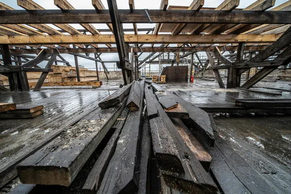 A gritty, high-contrast shot of your hands—scarred and dusty—holding a level or a framing square. Or, a wide shot of a heavy timber frame against a morning sky. No filters, just raw reality.