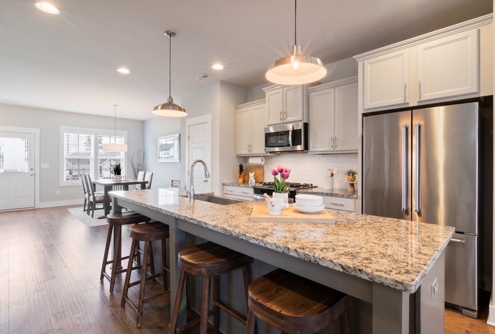 clean kitchen with beautiful lights on and dining room in the background