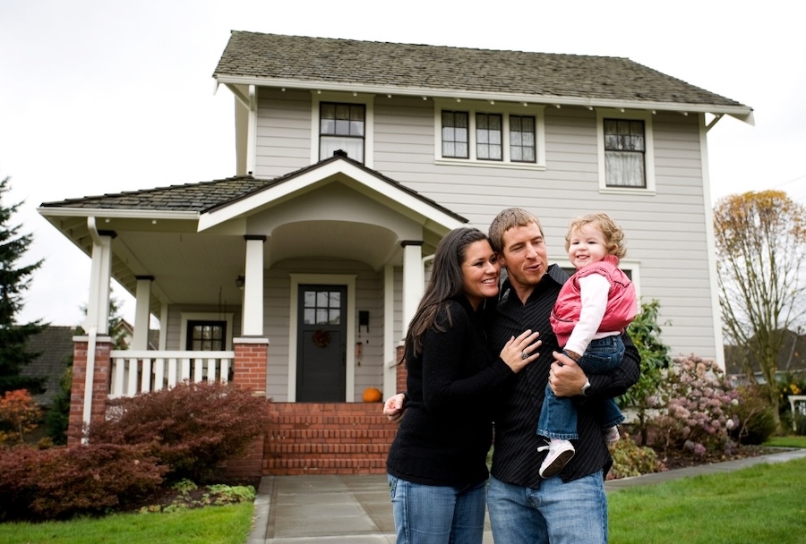 parents with daughter in front of their house smiling
