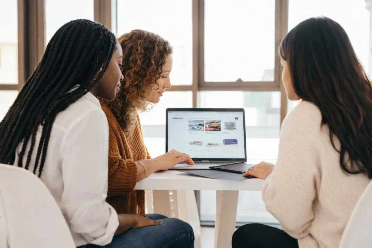 two women talking while looking at laptop computer