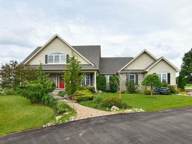 Two-storey craftsman-style home with gabled roof, red front door, stone and siding exterior, landscaped gardens, and paved driveway in Island Lake Estates, Mono