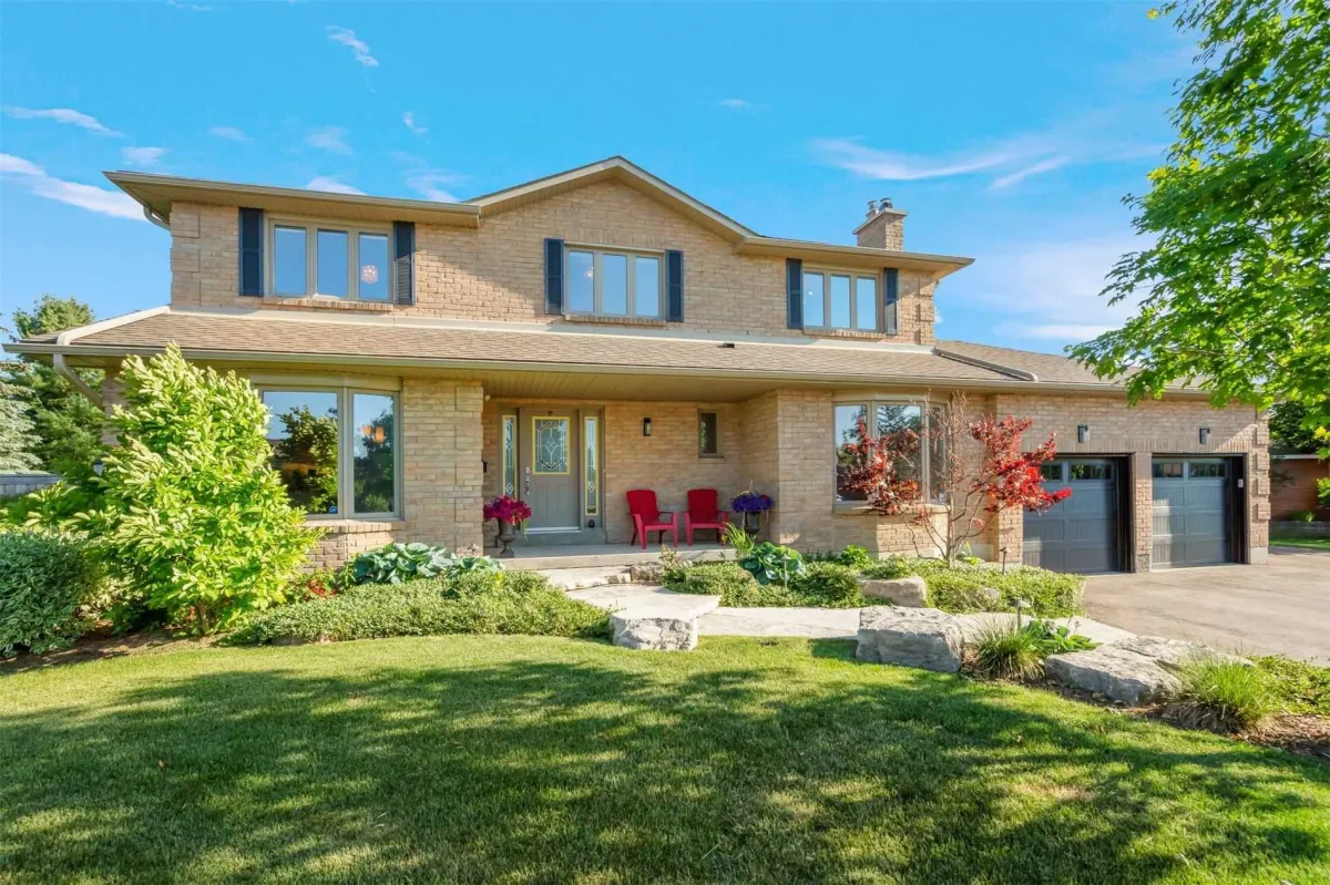 Light brick 2-storey detached home with attached 2-car garage, stone walkway and lush green lawn in the Purple Hill neighbourhood of Mono