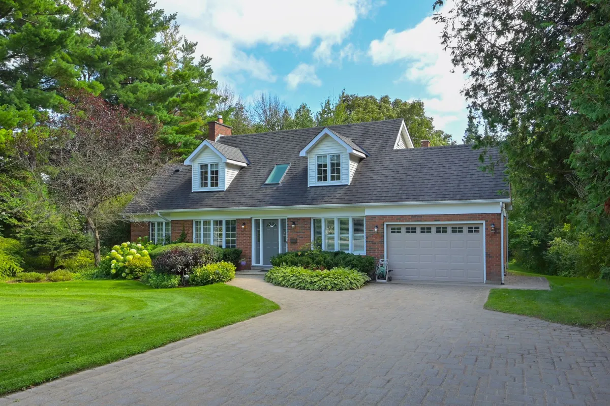 2-storey detached red brick home with brick driveway and mature gardens in the Starrview Acres neighbourhood in Mono