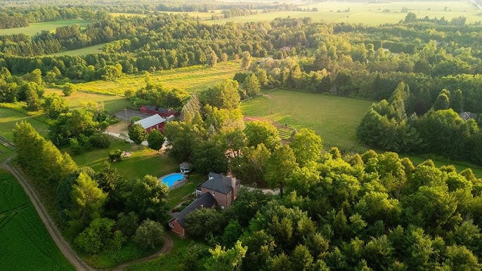 Aerial image of a spacious rural home with a pool and a barn on farm land located within the Mono Centre area of Mono, Ontario