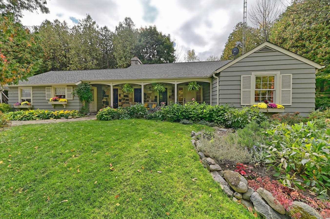 Bungalow home surrounded by mature gardens and trees in the Kilgorie area of Mulmur Township