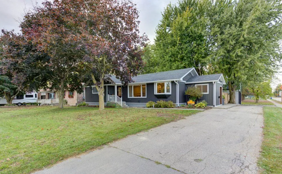 Blue bungalow with a large lot and mature trees located in Arthur, Ontario