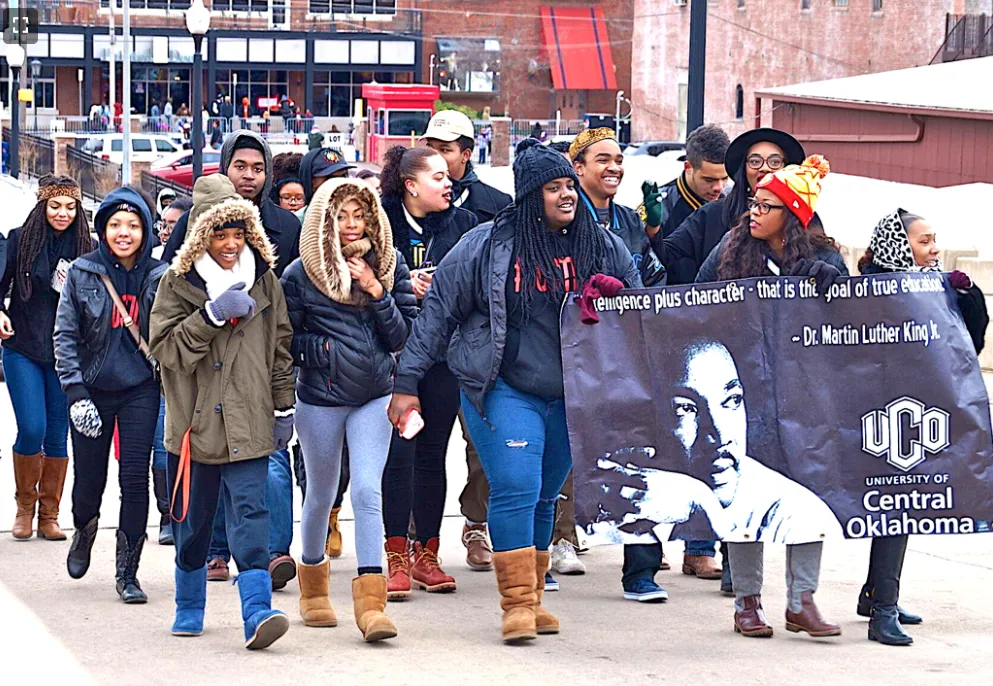 OKC MLK Day Parade crowd marching down Broadway with banners and flags