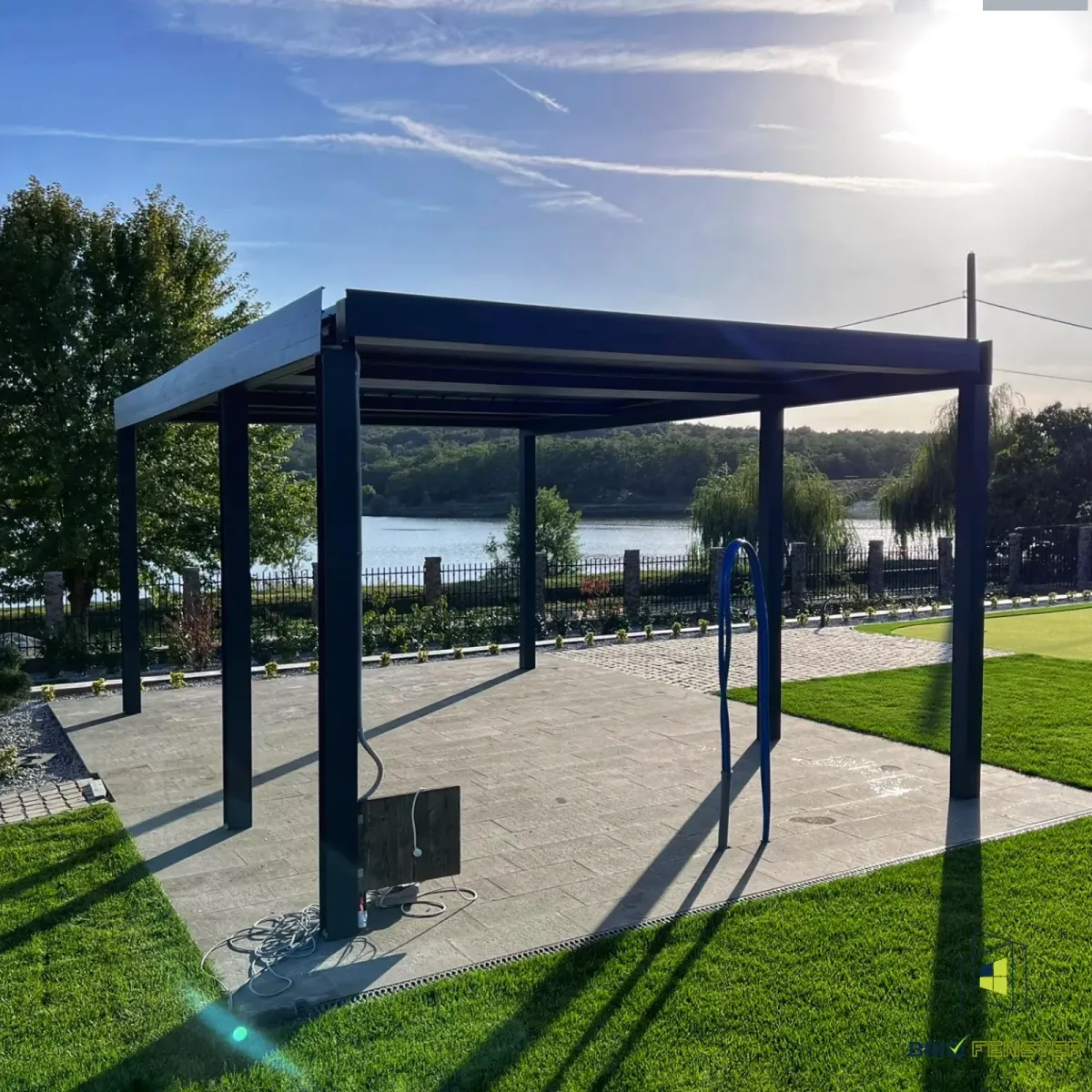 Pergola modernă dicu cadru metalic negru, montată într-o construcție nouă din beton.