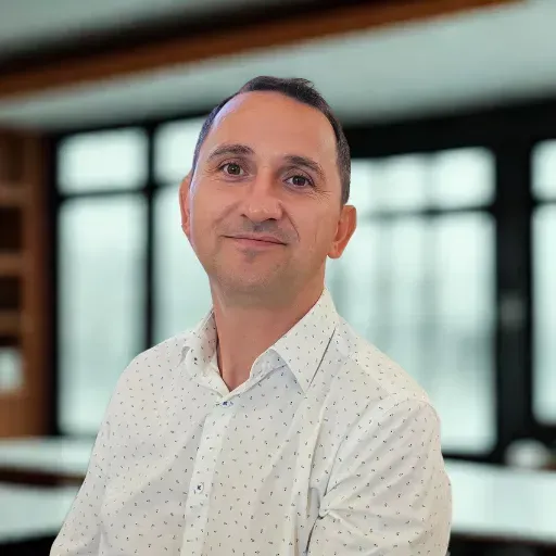 Portret al unui bărbat profesionist într-un birou modern, purtând o cămașă albă cu model discret.