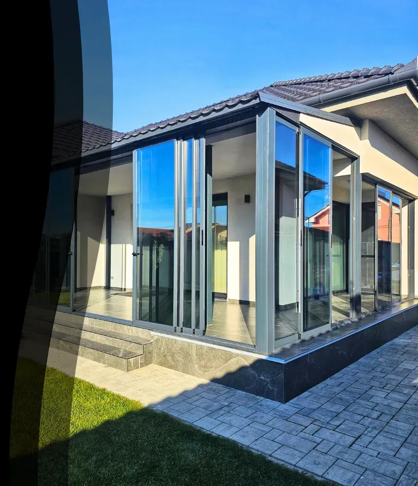 Sistem pliant din sticlă pentru terasă închisă, montat pe o casă modernă cu finisaje elegante.