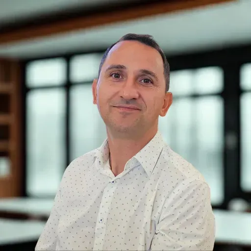 Portret al unui bărbat profesionist într-un birou modern, purtând o cămașă albă cu model discret.