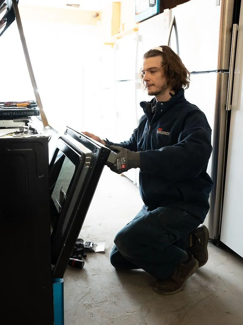 Al's Appliance technician inspecting an oven door during a spring appliance maintenance check