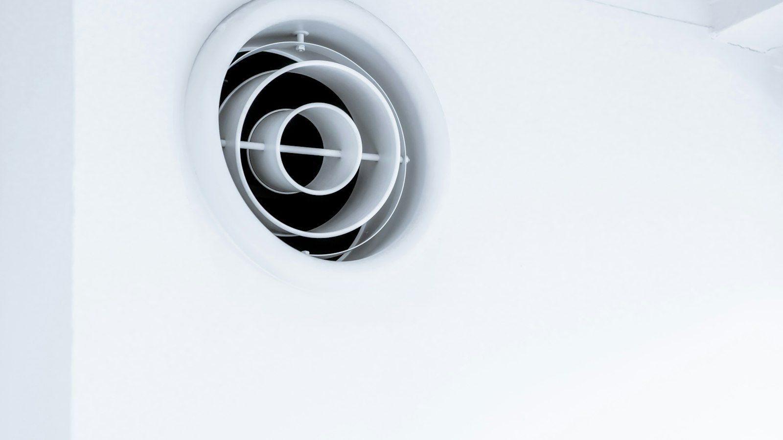 Round exhaust vent on a white exterior wall