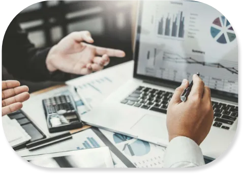 Hands gesturing towards a laptop displaying graphs, alongside papers and a calculator on a table.
