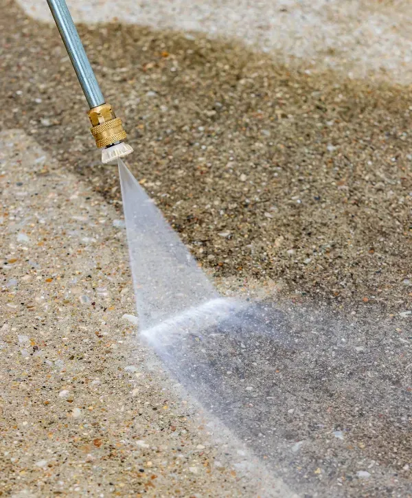 Close-up of pressure washer nozzle cleaning a concrete surface with high pressure water.