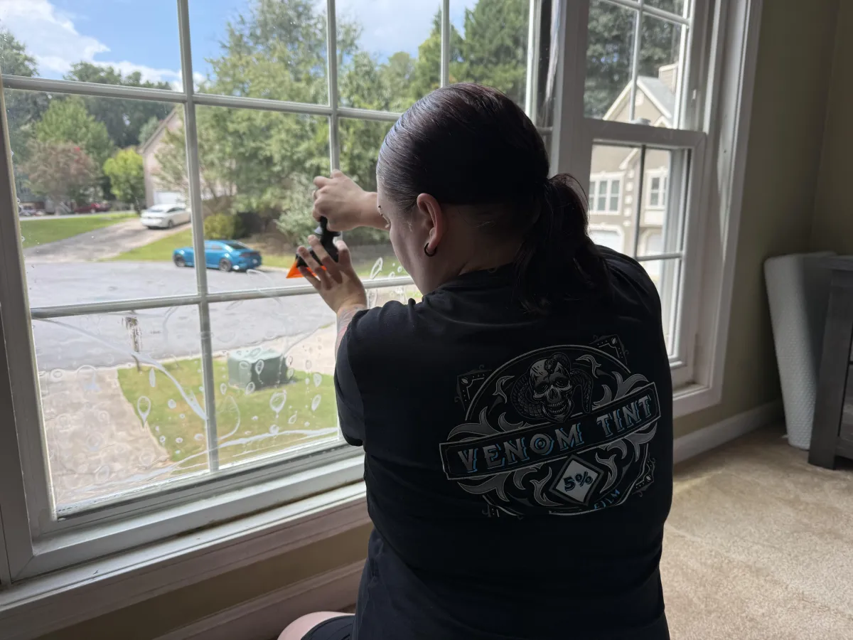 Venom Tint installer applying film to a residential window