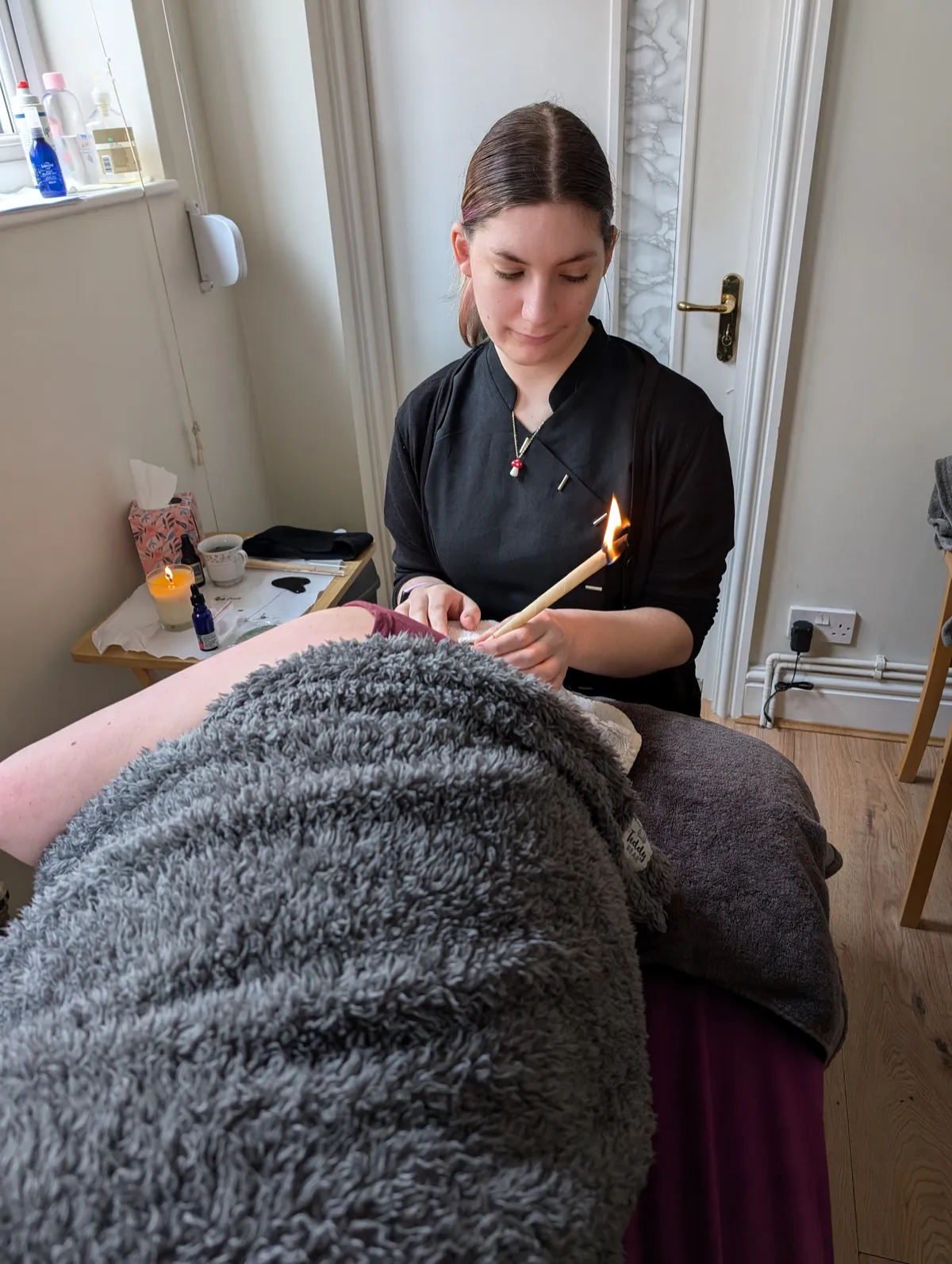A lit ear candle resting on natural linen for Thermal Auricular Therapy