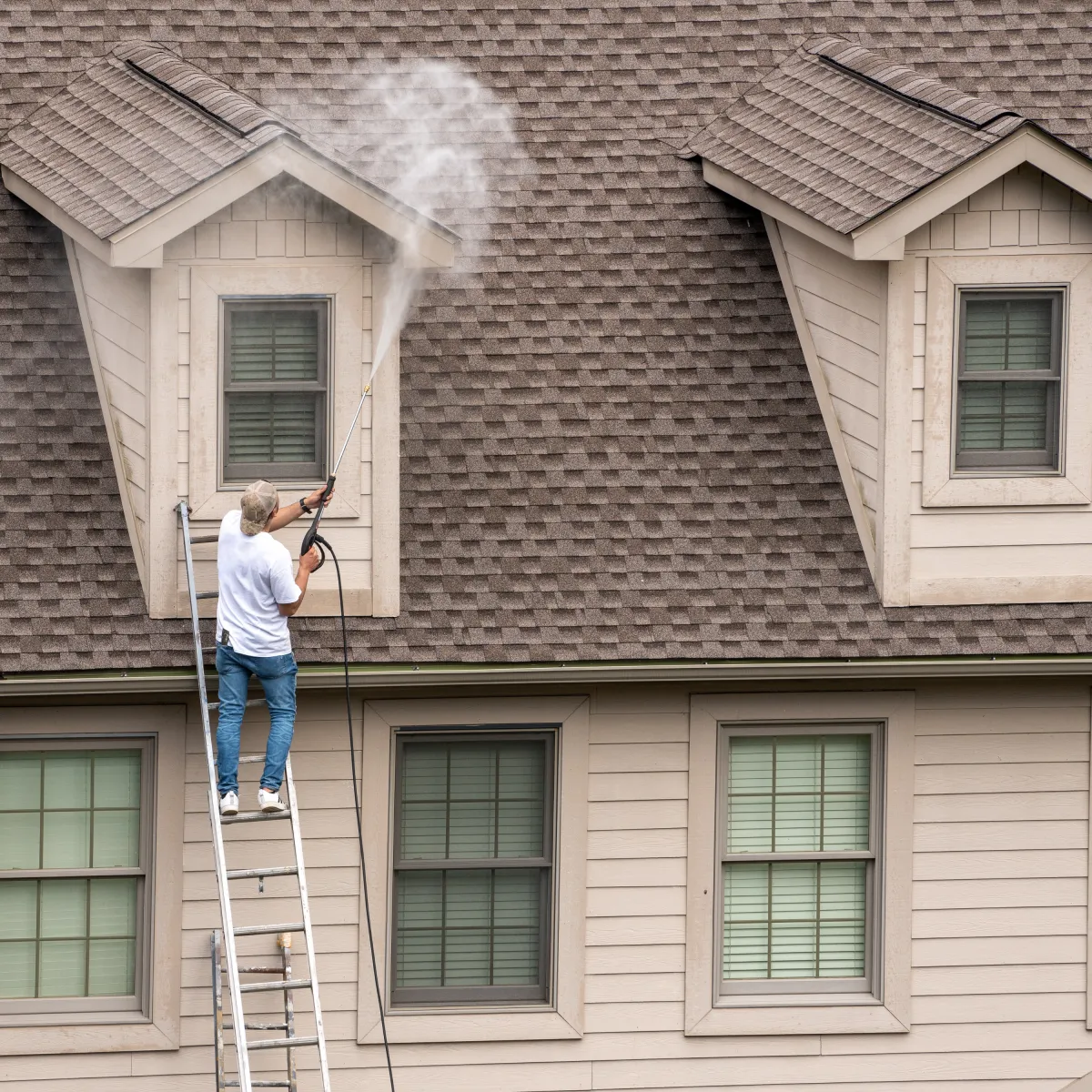 a man on a ladder washing a roof in long beach